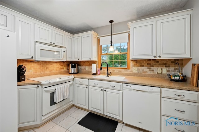 kitchen with light tile patterned flooring, white appliances, tasteful backsplash, a sink, and decorative light fixtures