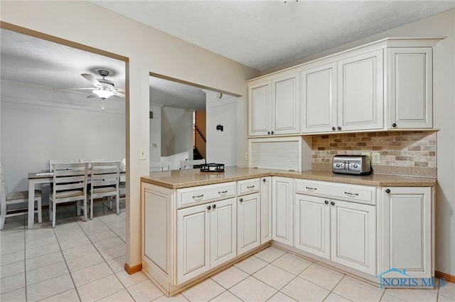 kitchen with decorative backsplash, a ceiling fan, light countertops, a peninsula, and light tile patterned flooring