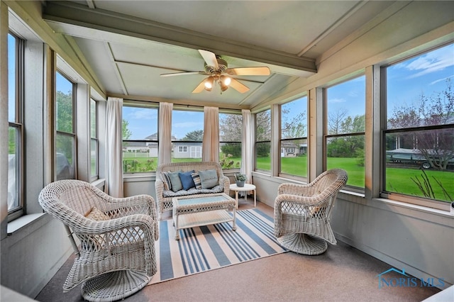 sunroom / solarium featuring beamed ceiling, ceiling fan, and an outdoor hangout area