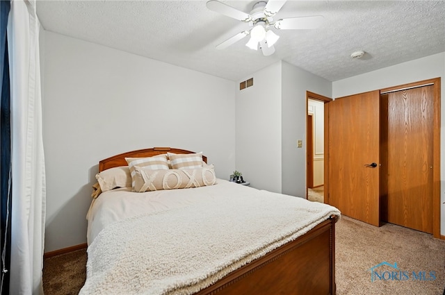 bedroom with a ceiling fan, a textured ceiling, visible vents, and light carpet