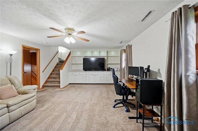 office featuring visible vents, a ceiling fan, a textured ceiling, and light carpet