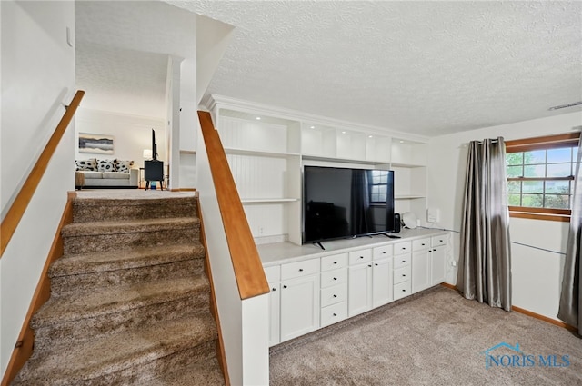 stairway featuring carpet, a textured ceiling, and visible vents