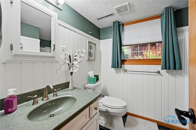bathroom featuring visible vents, a textured ceiling, toilet, and vanity