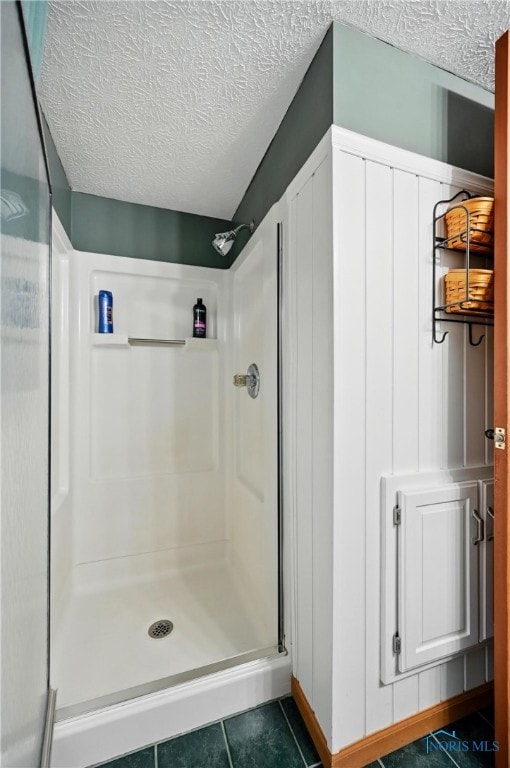 full bathroom with tile patterned floors, a shower stall, and a textured ceiling