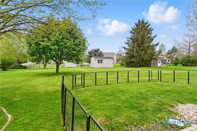 view of yard featuring a storage shed, fence, and an outbuilding