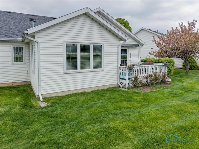 rear view of property with a shingled roof, a yard, and a deck