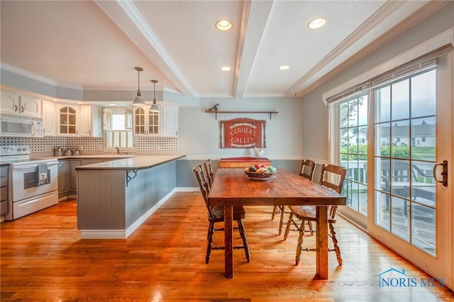 dining area featuring crown molding, wainscoting, beamed ceiling, recessed lighting, and light wood-style flooring