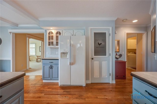 kitchen with ornamental molding, washer and dryer, light wood finished floors, and white refrigerator with ice dispenser