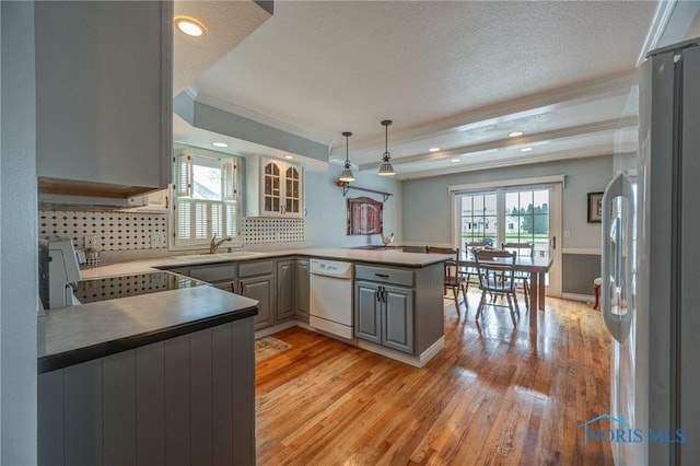 kitchen with white dishwasher, crown molding, freestanding refrigerator, light wood finished floors, and a peninsula