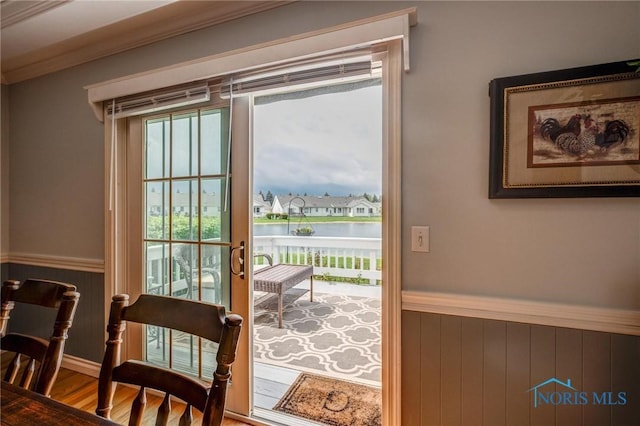 doorway to outside with wooden walls, a water view, wood finished floors, and a wainscoted wall