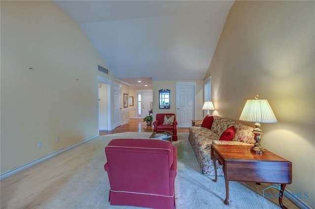 carpeted living area featuring high vaulted ceiling, baseboards, and visible vents