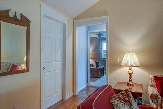 interior space with baseboards, wood finished floors, and lofted ceiling