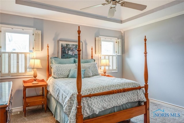 carpeted bedroom with a ceiling fan, baseboards, ornamental molding, and a tray ceiling
