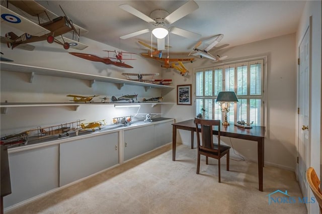 home office with a ceiling fan, baseboards, and light colored carpet