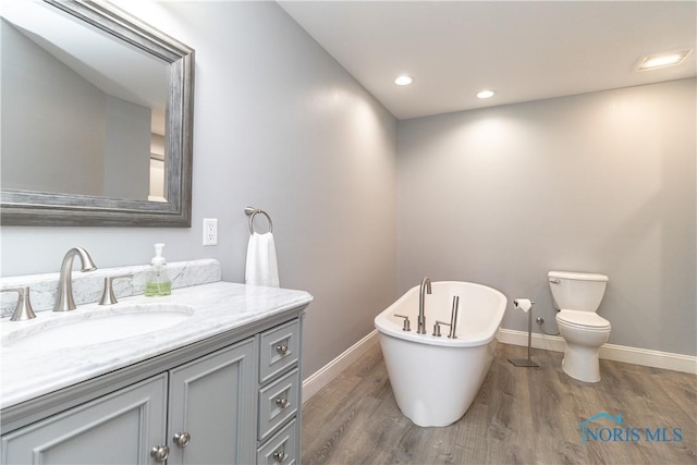 749 Parkside Dr, Wauseon, OH 43567 - bathroom featuring a freestanding bath, wood finished floors, vanity, baseboards, and toilet