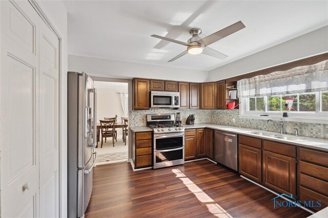 106 N Munson Rd, Swanton, OH 43558 - kitchen featuring appliances with stainless steel finishes, a sink, dark wood-style flooring, light countertops, and tasteful backsplash