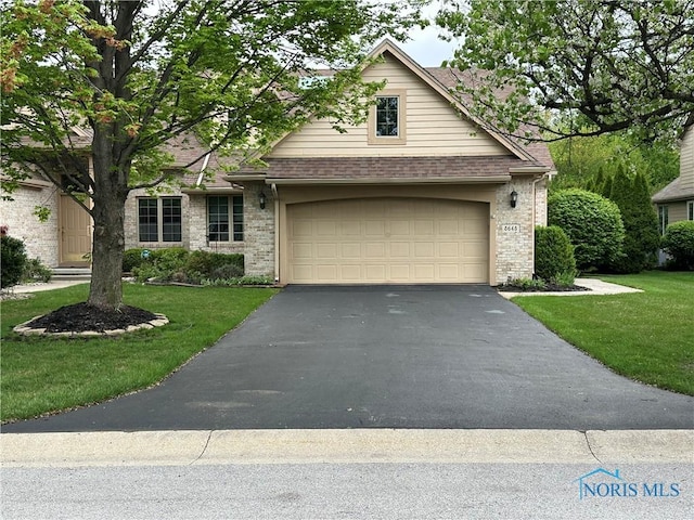 view of front of home featuring a front yard, brick siding, and aphalt driveway