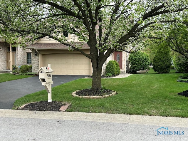 obstructed view of property featuring a garage, a front lawn, and aphalt driveway