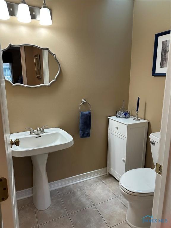 bathroom featuring toilet, baseboards, and tile patterned flooring