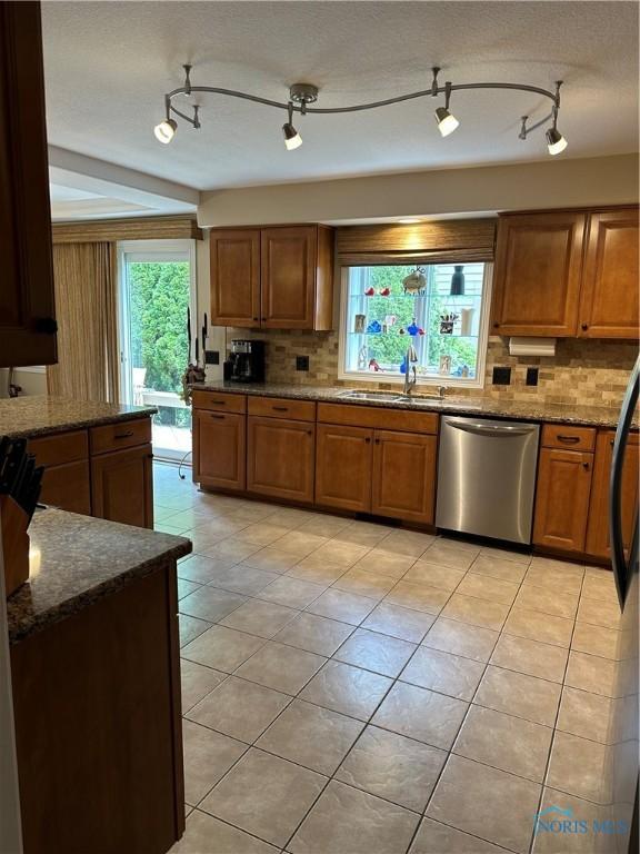 kitchen with brown cabinetry, decorative backsplash, a sink, and dishwasher