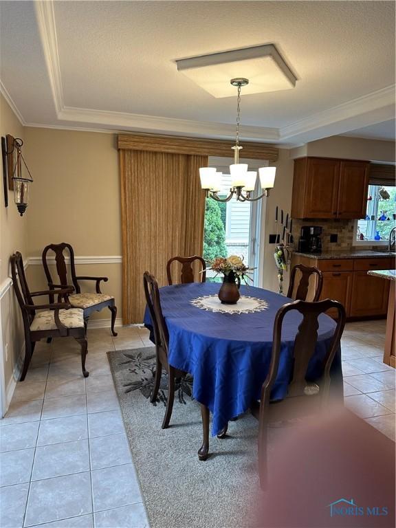 dining area featuring crown molding, light tile patterned flooring, and a chandelier