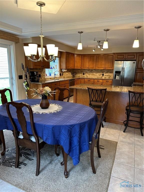 dining area with light tile patterned floors, a chandelier, ornamental molding, and a healthy amount of sunlight
