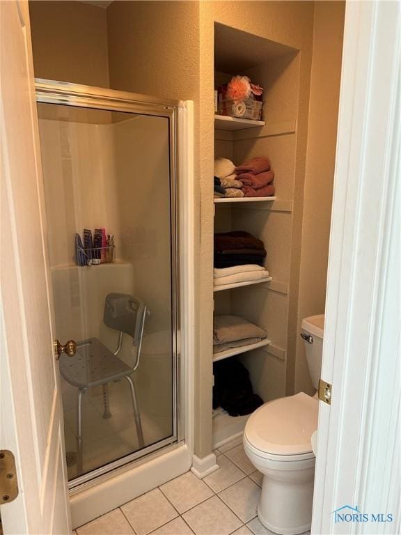 full bath with toilet, tile patterned flooring, and a stall shower