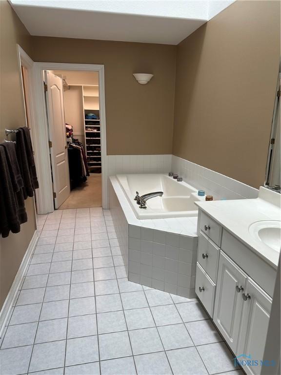 full bath featuring vanity, tile patterned floors, a garden tub, and a spacious closet
