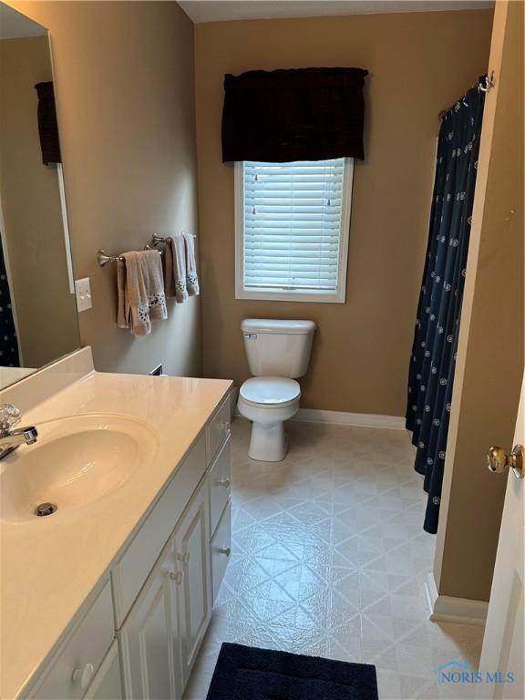 bathroom with baseboards, vanity, and toilet