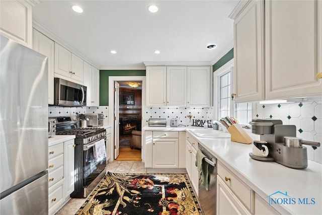 3766 Edgevale Rd, Toledo, OH 43606 - kitchen with stainless steel appliances, a sink, decorative backsplash, light countertops, and white cabinets