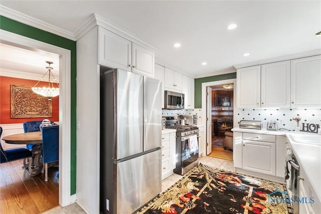 3766 Edgevale Rd, Toledo, OH 43606 - kitchen featuring appliances with stainless steel finishes, crown molding, a chandelier, white cabinets, and decorative backsplash