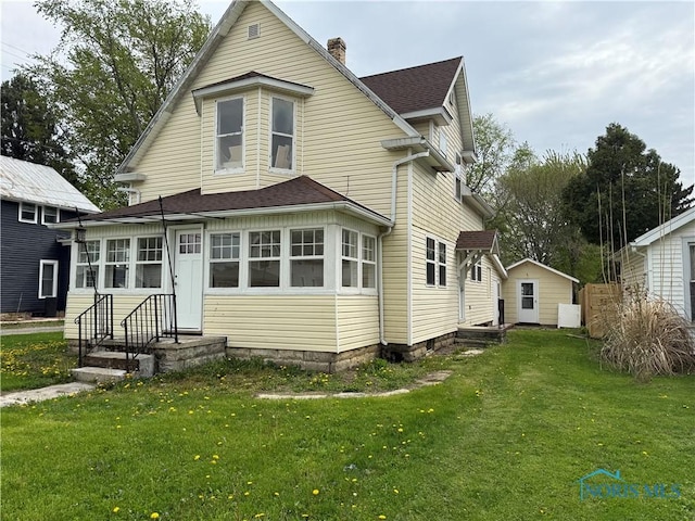 view of front of home featuring a shingled roof, a chimney, and a front lawn