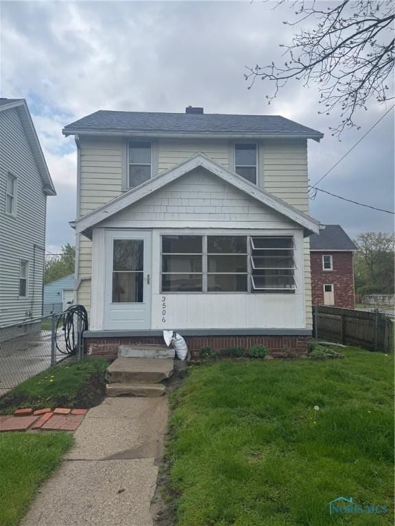view of front of house with entry steps, fence, a shingled roof, and a front yard