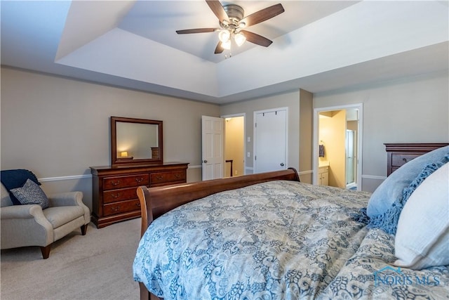 bedroom with carpet flooring, connected bathroom, ceiling fan, a raised ceiling, and baseboards