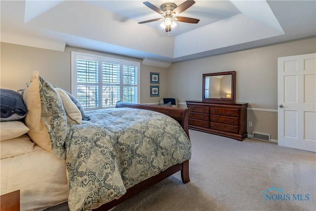 bedroom with a ceiling fan, carpet, a tray ceiling, and visible vents