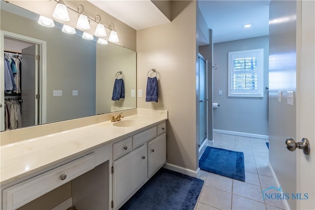 full bath with baseboards, tile patterned flooring, a shower stall, and vanity