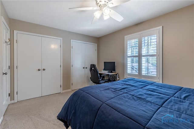 carpeted bedroom with two closets, a ceiling fan, and baseboards