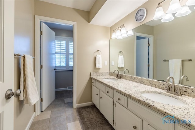 full bath featuring baseboards, a sink, a notable chandelier, and double vanity