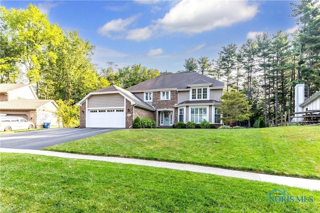 traditional home featuring brick siding, a garage, aphalt driveway, and a front yard