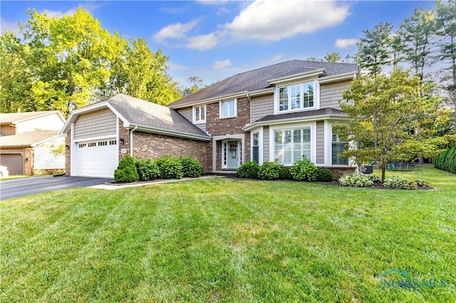 traditional-style house with brick siding, a garage, aphalt driveway, and a front yard