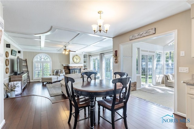 dining room with a glass covered fireplace, ceiling fan with notable chandelier, coffered ceiling, and hardwood / wood-style flooring