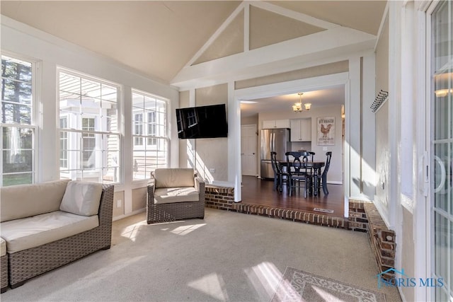 carpeted living area featuring an inviting chandelier and high vaulted ceiling