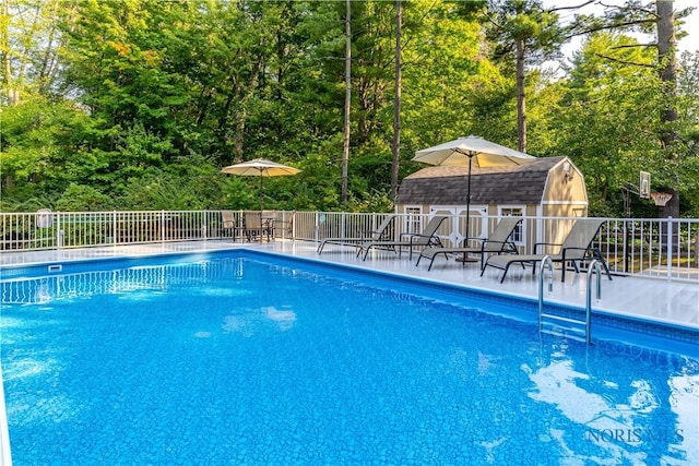view of pool with fence, a fenced in pool, and an outbuilding