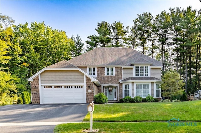 traditional home with a garage, a front yard, brick siding, and aphalt driveway