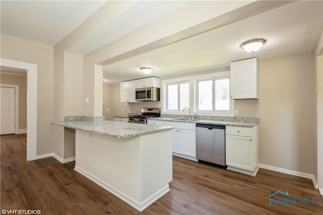 303 Short St, Napoleon, OH 43545 - kitchen featuring baseboards, light stone counters, a peninsula, stainless steel appliances, and white cabinetry