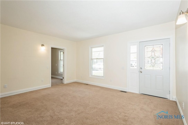 entrance foyer featuring baseboards, visible vents, and light carpet