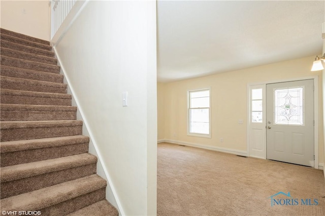 entryway with baseboards, carpet, and stairway