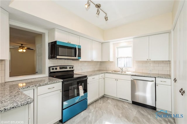 kitchen featuring light stone countertops, white cabinets, tasteful backsplash, a sink, and appliances with stainless steel finishes