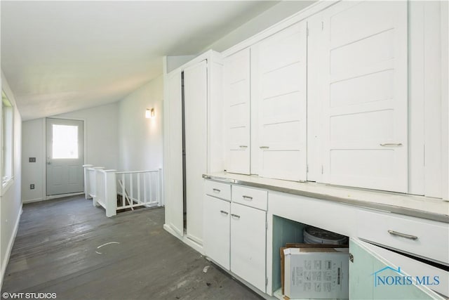 interior space with dark wood-style flooring, baseboards, an upstairs landing, and lofted ceiling