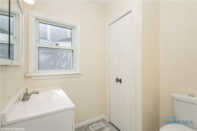 half bathroom with visible vents, baseboards, toilet, and vanity